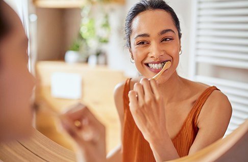 Woman smiling while brushing her teeth