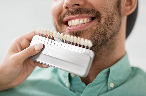 Several veneers next to a dental mirror on a black surface