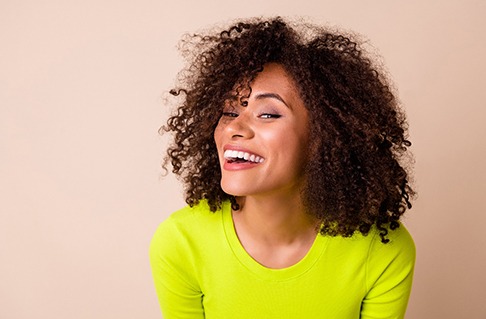 Man smiling with a shade guide held to his teeth