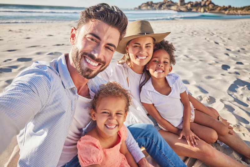 Family smiling on the beach after teeth whitening