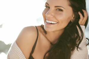 Woman smiling and touching her hair with sunlight behind her